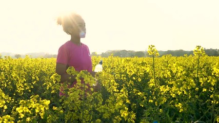 Beautiful healthy mixed race African American girl teenager female young woman resting after running or jogging in field of yellow flowers