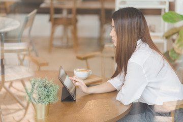 Young attractive Asian woman is using tablet and smartphone in coffee shop cafe, online content...