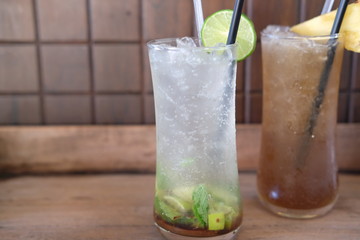 glass of cocktail with ice and mint on wooden table