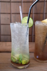 glass of cocktail with ice and mint on wooden table