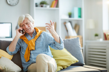 Portrait of frowning senior man speaking by phone arguing with somebody, copy space
