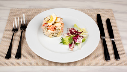 Salad Olivier with egg and cabbage on a white plate.