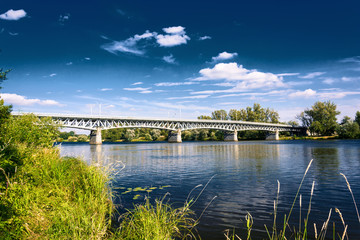 Steel bridge across the river Elbe in the town of Litomerice in the Czech Republic. Bridge in summer sunny day. Metal construction of arched bridge with pillars over the river. Architectural monument 