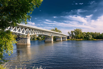 Steel bridge across the river Elbe in the town of Litomerice in the Czech Republic. Bridge in summer sunny day. Metal construction of arched bridge with pillars over the river. Architectural monument 