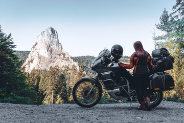 Fototapeta premium Woman biker and adveture motorcycle on mountain road in Bicaz Canyon, Romania. Travel concept, extreme, vacation in Europe, motorcyclist way, tourism, Cheile Bicazului, Europe. copy space