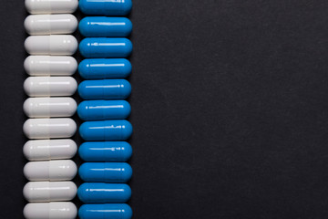 Lines of white and blue tablets on a dark background. Mock-up