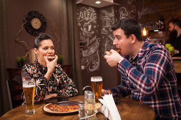 Happy couple drinking beer and eating pizza.