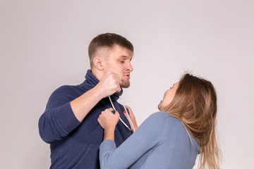 people, domestic violence and abuse concept - young man threatens his wife with his fist on white...