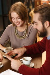 You should try this. Vertical top view shot of a handsome bearded man showing something to his girlfriend in the menu at local cafe