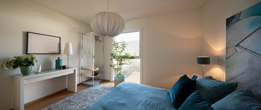 Elegant and minimalist bedroom, bed with blue blankets and pillows