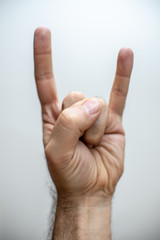 Hand doing a metal sign over white background