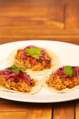 Tasty juicy tacos with pulled pork meat, salsa and marinated onion