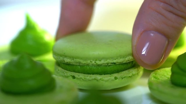 Chef connecting two halves of green pistachio macaroons with cream. Macarons - delicious and beautiful french dessert. Cooking, food and baking, pastry shop concept. 4k
