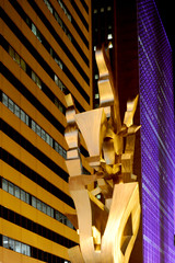Gold art sculpture at night in the streets of Chicago with skyscrapers in the background. 