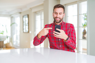 Handsome man using smartphone very happy pointing with hand and finger