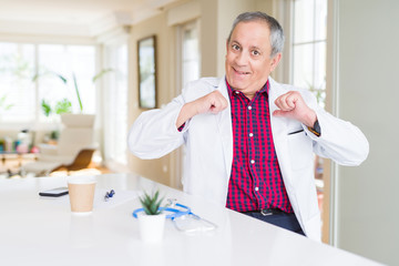 Handsome senior doctor man wearing medical coat at the clinic looking confident with smile on face,...