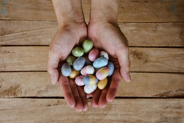 Hand woman holding colorful easter eggs on wood table background.