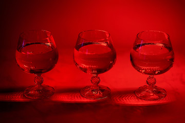 three glasses of water or wine on a red background