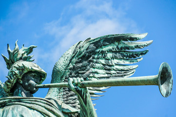 Angel statue playing the trumpet in front of blue sky