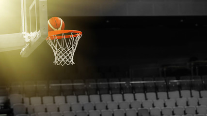 Basketball ball flies into the basketball hoop on the background of the stands of the sports complex