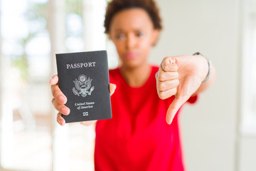 Young african american woman holding passport of United States of American with angry face, negative sign showing dislike with thumbs down, rejection concept