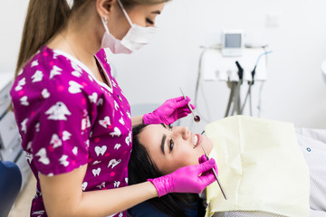 Dentist examining patient teeth with a mouth mirror and dental excavator.