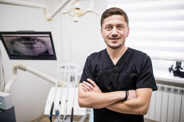 Portrait of man dentist standing in front of in dentist office