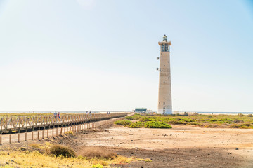 Lighthouse and wooden bridge with tourists in Morro Jable, Fuerteventura, Spain