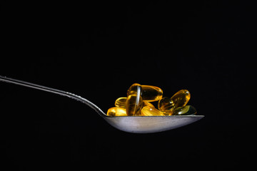 Metal silver spoon with the omega 3 in it. Large side view. Black dark background. Plenty of room...