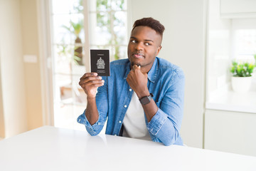 African american man holding passport of Canada serious face thinking about question, very confused...