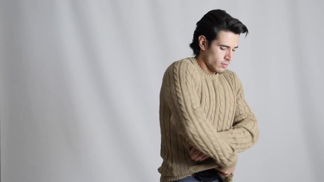 Fit athletic young man removing winter wool sweater on black t-shirt, undressing and taking it off