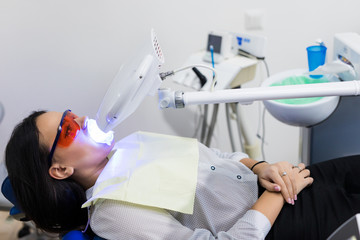 Laser bleaching teeth at dantist room. Teeth whitening for woman. Bleaching of the teeth at dentist clinic.