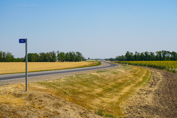 Rotation of the highway in Russia in the Rostov region near a field sown with wheat and sunflowers....