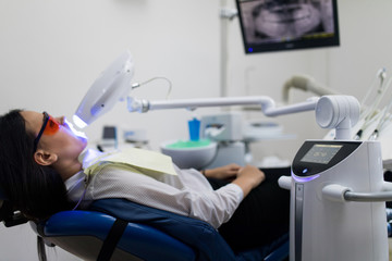 Portrait of young woman visiting dentist office for teeth whitening with photopolymer. Dental care.