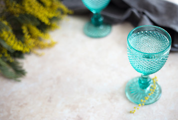 Blue Vintage Goblets and yellow mimosa flowers . Wineglasses on whight background.