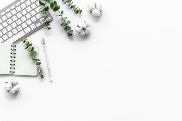 Laptop, cotton branch on white table flat lay copy space. Minimal freelancer home office desk workspace.