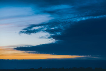 Cityscape with wonderful varicolored vivid dawn. Amazing dramatic blue cloud sky above dark...