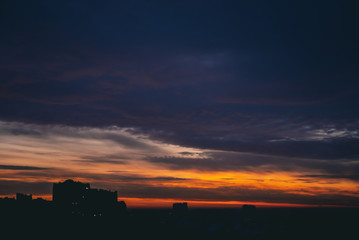 Cityscape with wonderful varicolored fiery dawn. Amazing dramatic multicolored cloudy sky. Dark...