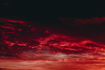 Fiery red blood vampire dawn. Amazing warm dramatic fire cloudy sky. Vivid orange sunlight. Atmospheric background of sunrise in overcast weather. Hard cloudiness. Storm clouds warning. Copy space.