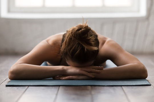 Young woman practicing yoga, relaxing after training, lying face down