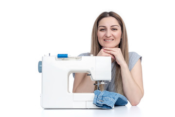 Young woman sews on a sewing machine, isolated on white background 