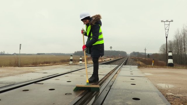 Female railway worker clean railway crossing in winter