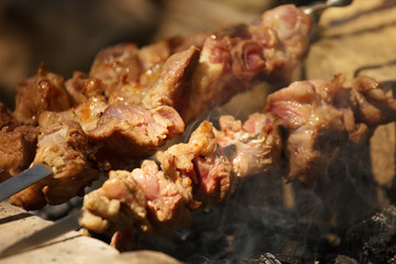 Slices of pork being cooked on an open fire