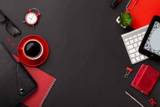 Black background red coffee cup notepad alarm clock flower diary scores keyboard on the table. Top view with copy space
