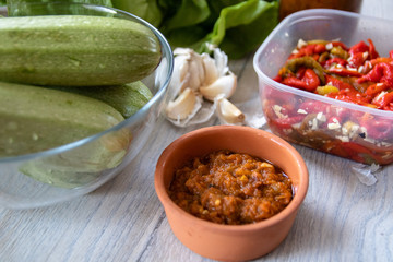 Homemade pickled paprika with garlic, zucchini, lettuce, garlic cloves and sauce on wooden table