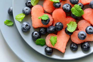 Plate with summer watermelon salad with blueberry and mint leaves on gray plate. Healthy eating concept. Top view