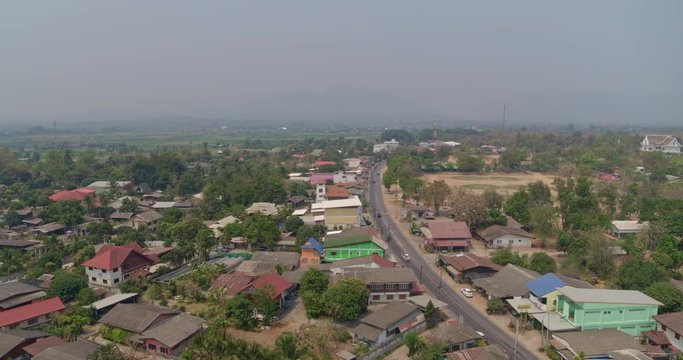 Ban Kad Thailand Aerial v3 Flying low over houses following path of main thoroughfare with cars - March 2018