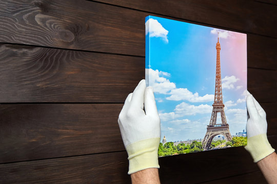 Photography printed on canvas with gallery wrap method of canvas stretching in male hands. Image of Eiffel Tower (Paris, France)