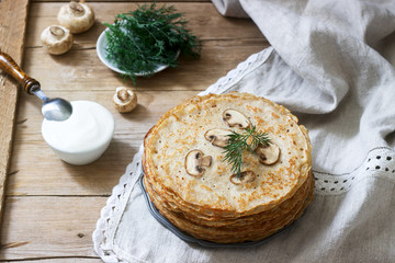 Buckwheat pancakes served with sour cream and dill on a wooden table. Rustic style.