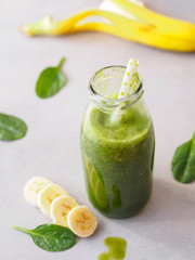 Grüner Smoothie mit Blattspinat und Banane in einer Glasflasche mit Strohalm